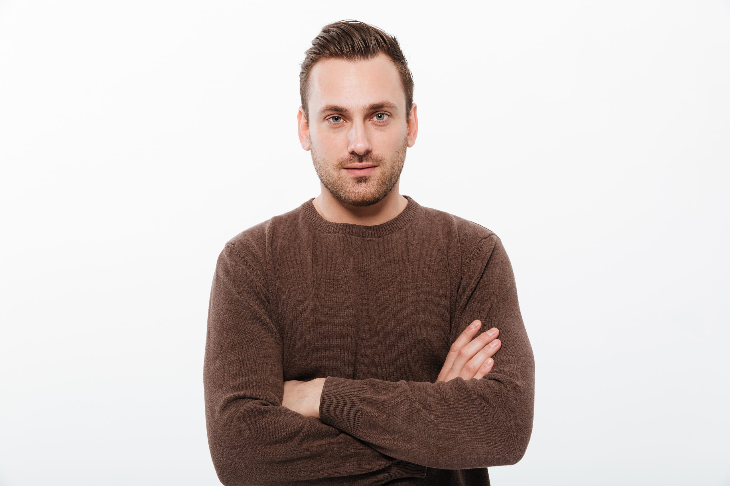 Handsome young serious man with arms crossed. Looking camera.
